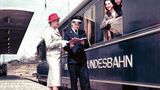 Werbemotiv der Bahn aus den späten 1950er Jahren: Fotomodelle am Fenster eines blauen Schürzenwagens für den Schnellzugverkehr  im Heidelberger Hauptbahnhof.