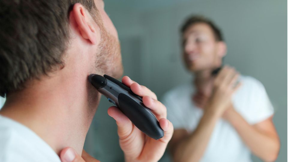Ein Mann rasiert sich mit einem elektrischen Rasierer