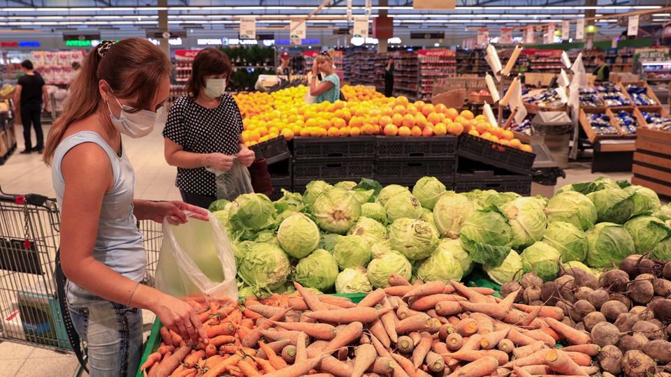 Eine junge Frau packt Karotten im Supermarkt ein