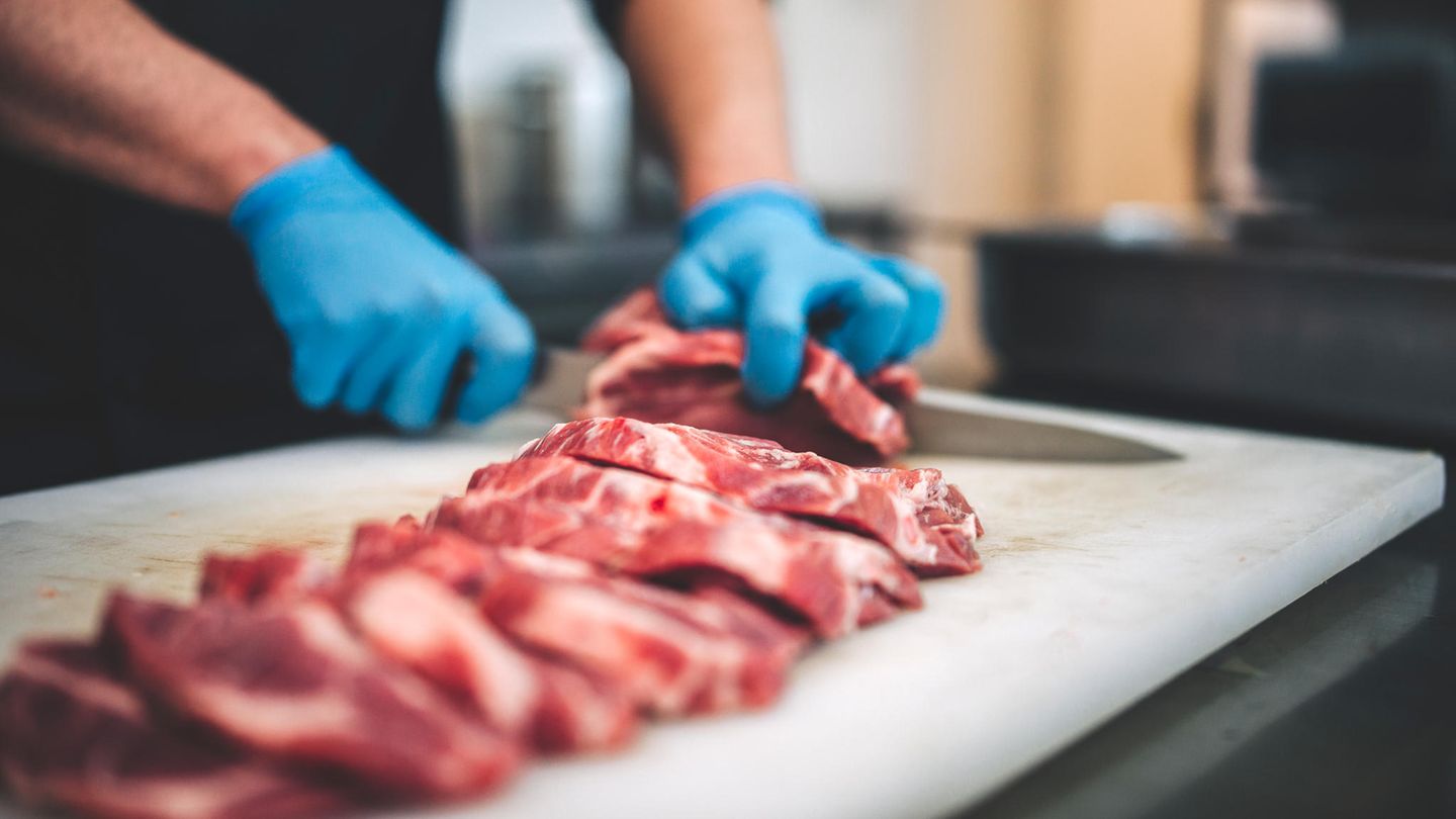 Ein Mann schneidet rohes Fleisch