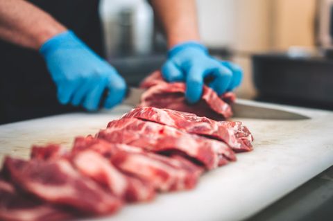 Ein Mann schneidet rohes Fleisch