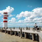 Eine runde Sache: Neusiedler See Radweg  Rust – Podersdorf oder Purbach – "Neusiedl am See  Der Vorteil an Rundwegen: Man kann starten, wo man möchte, und kommt doch überall vorbei. Rust aber, ein kleines Städtchen auf der Westseite des Neusiedler Sees, ist besonders empfehlenswert als Startpunkt am frühen Morgen: Wenn die Störche in ihren Nestern erwachen, paddeln wir aus der Ruster Bucht hinaus auf den größten See Österreichs. Wobei wir uns eher in fernen Gefilden wähnen. Luftsprünge erlaubt, bei Hechtsprüngen Vorsicht: Der See ist nirgends tiefer als 1,80 Meter. Wieder am Ufer, lässt man die Windrichtung entscheiden, wohin der Lenker zeigen soll. Nach Süden? Dann kürzt man in Mörbisch per Fähre nach Illmitz ab und ist plötzlich mittendrin im Nationalpark: zwischen Salzlacken und Schilf und Reihern und Löfflern, die ihren Geschäften nachgehen und Futter suchen. Das sollte man auch.  Mögliche Fundstelle: in Podersdorf, im Gastgarten "Zur Dankbarkeit", könnte es zum Beispiel ein gebratener Zander mit einem Glas Muskateller sein. Ist man dagegen von Rust nach Norden gestartet, sollte man ein Mittagessen in Purbach anpeilen. Beim Spritzwein in einem der 50 kühlen Weinkeller der Purbacher Kellergasse ist die Gefahr allerdings groß, selbst zum Löffler zu werden und den Schnabel zu tief ins Glas zu stecken. Passiert? Das nächste Seebad für einen Mittagsschlaf ist nicht weit. Es reicht, zum Sonnenuntergang in Neusiedl am See zu sein. Der lässt sich übrigens auf die Minute bestimmen: Die Bar "Mole West" bietet die Sonnenuntergangszeit immer aktuell auf ihrer Startseite an. Damit man spätestens um beispielsweise 18.33 Uhr auf der Seeterrasse ein Glas Welschriesling in der Hand hält.