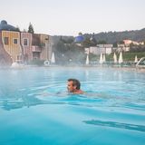 Die The(r)men-Tour  Eurovelo Nr. 9:  "Bad Waltersdorf" – "Bad Blumau" – "Bad Loipersdorf" – " Bad Radkersburg  Von der Ostsee bis an die Adria geht die Euro- Velo 9, und so schneidet sie einmal längs durch Österreichs Osten. Anfangs genießt man das Wasser vorrangig in veredelter Form als Wein, immerhin radelt man durchs Weinviertel, die Heimat des Grünen Veltliners, und bald danach durch Wien. Aber schon kurz nach der Hauptstadt begegnet uns das Wasser in anderer Form: Es wird thermal. Die strapazierten Knochen und Muskeln wird’s freuen.  Ein abendliches Schwefelbad in der Römertherme Baden ist dabei nur der Anfang. Denn hat man im berühmten Wienerwald und den Wiener Alpen das Grün und die Gipfel genossen, gelangt man ins Thermen und Vulkanland Steiermark, wo vielerorts das Wasser bis zu 110 Grad heiß aus der Tiefe sprudelt. Aber wo anhalten? Am besten überall. In der Heiltherme Bad Waltersdorf hat das Wasser, wie der Name schon sagt, Heilkräfte. Nachweislich auch bei Muskelkater (Selbstversuch). In der von einem gewissen Hundertwasser gestalteten Therme Rogner Bad Blumau lässt man sich im salzigen Urmeer treiben. Das Wasser in Bad Loipersdorf soll besonders bei Gelenkbeschwerden förderlich sein. Das flüssige Highlight für Radelnde: Bad Radkersburg, die herrlich hübsche Stadt, die als Knotenpunkt von Murradweg, Weinland Steiermark Radtour und EuroVelo 9 fungiert. Dort, im Quellbecken der Parktherme, löst sich jedes Muskelzwicken in Wohlgefallen auf.