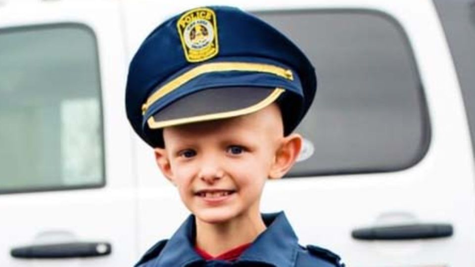 Junge mit Krebs wird für einen Tag Polizist Kleiner Junge mit Krebs in Polizeiuniform