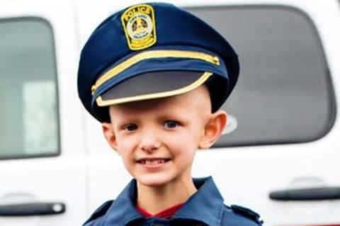 Kleiner Junge mit Krebs in Polizeiuniform