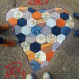 Zwei Menschen stehen neben einem Mosaik in Herzform, das Streetart-Künstler Ememem erstellt hat.