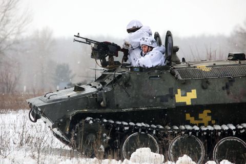 Zwei ukrainische Soldaten schauen während einer Militärübung aus einem gepanzerten Militärfahrzeug