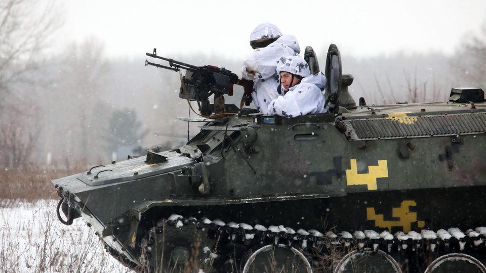 Zwei ukrainische Soldaten schauen während einer Militärübung aus einem gepanzerten Militärfahrzeug