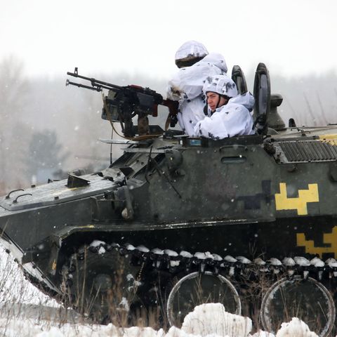 Zwei ukrainische Soldaten schauen während einer Militärübung aus einem gepanzerten Militärfahrzeug