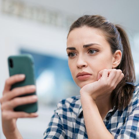 Frau sitzt besorgt vor ihrem iPhone