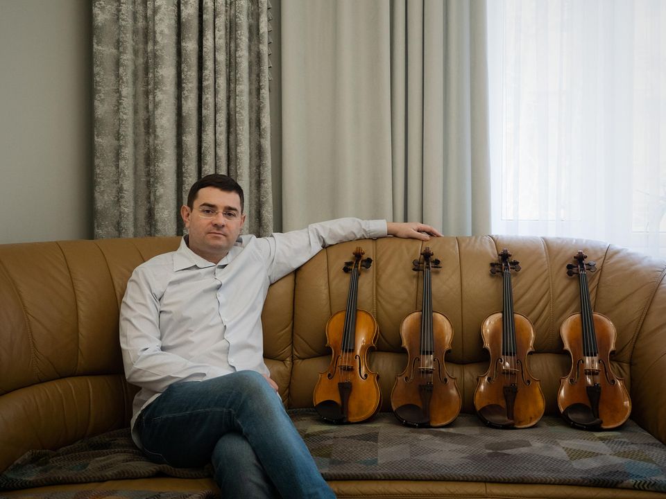 Orest Putsentela auf dem Sofa mit vier seiner gebauten Geigen