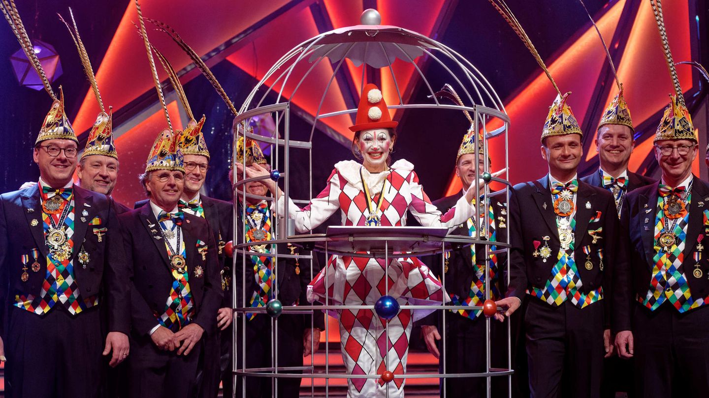 Iris Berben steht im Harlekinkostüm im Narrenkäfig