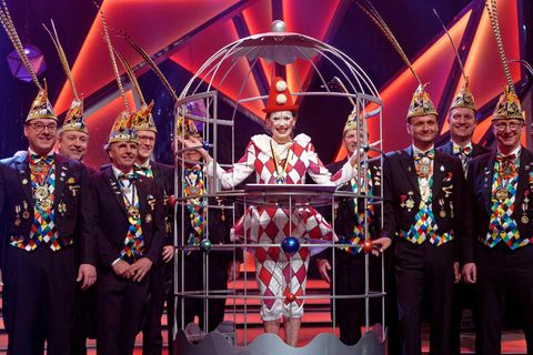 Iris Berben steht im Harlekinkostüm im Narrenkäfig