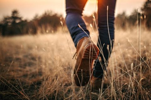 Wanderschuhe im Abendlicht laufen über eine Wiese