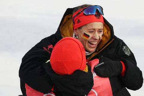 Katharina Hennig feiert die Goldmedaille mit einem Trainer, Co-Läuferin Victoria Carl ist nicht im Bild