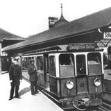 Zwei Schaffner mit Hut  stehen im Jahr 1902 vor der ersten U-Bahn, die damals in Berlin in Betrieb ging.