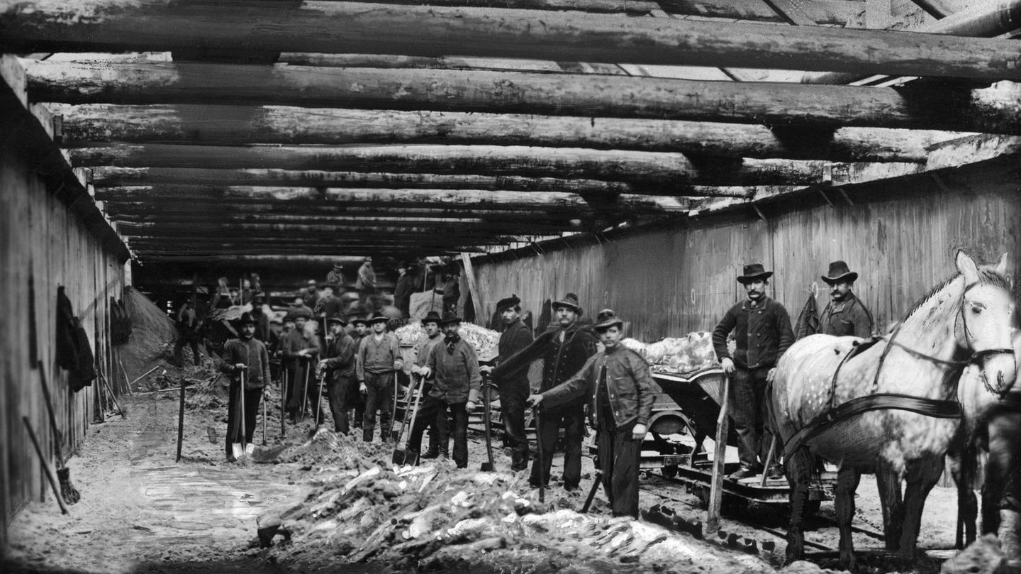 Männer mit Schaufeln und einem Pferd schauen beim Bau der Teilstrecke der Berliner U-Bahn im Jahr 1901 in die Kamera