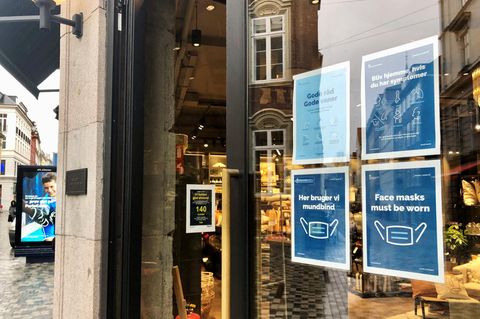Schilder weisen am Eingang eines Ladens in der Kopenhagener Innenstadt auf Corona-Maßnahmen hin