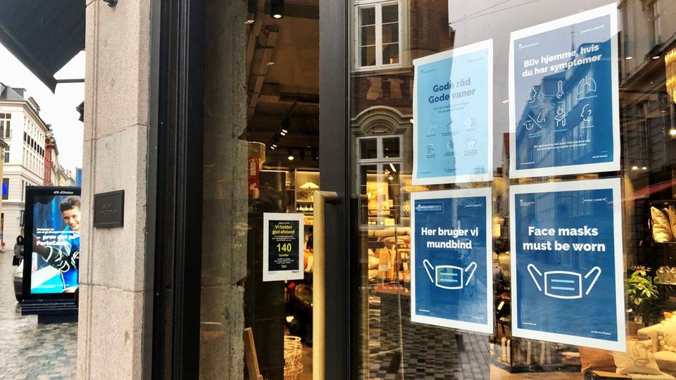 Schilder weisen am Eingang eines Ladens in der Kopenhagener Innenstadt auf Corona-Maßnahmen hin