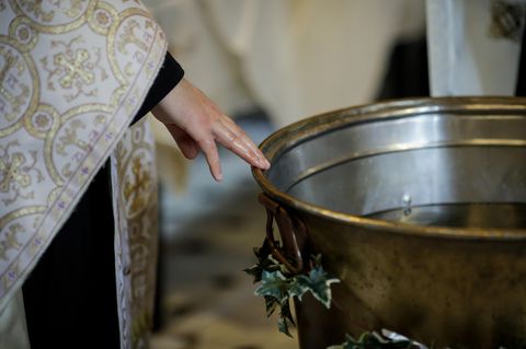 Ein Priester steht an einem Taufbecken
