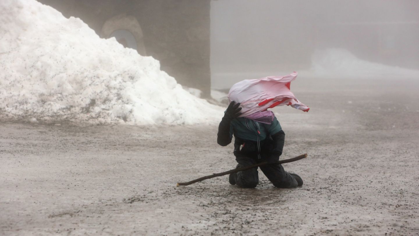 Ein junger Wanderer auf dem Brocken kämpft am Boden gegen starke Windböen
