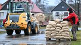Im strömenden Regen werden Sandsäcke von freiwilligen Helfern verteilt.