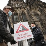 "Vorsicht Steinschlag" steht auf einem Schild, das Mitarbeiter des Doms aufstellen