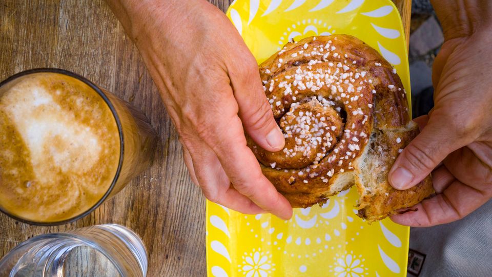 Fika Schweden Achtsamkeit Arbeit Zwei Hände halten eine Zimtschnecke
