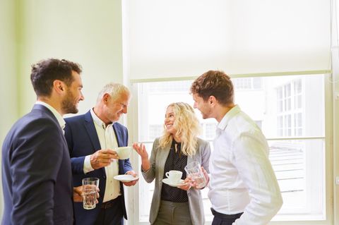 Büro-Angestellt unterhalten sich bei einer Tasse Kaffee