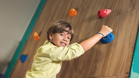 Klettersteine für Kinder: Junge an einer Indoor-Kletterwand