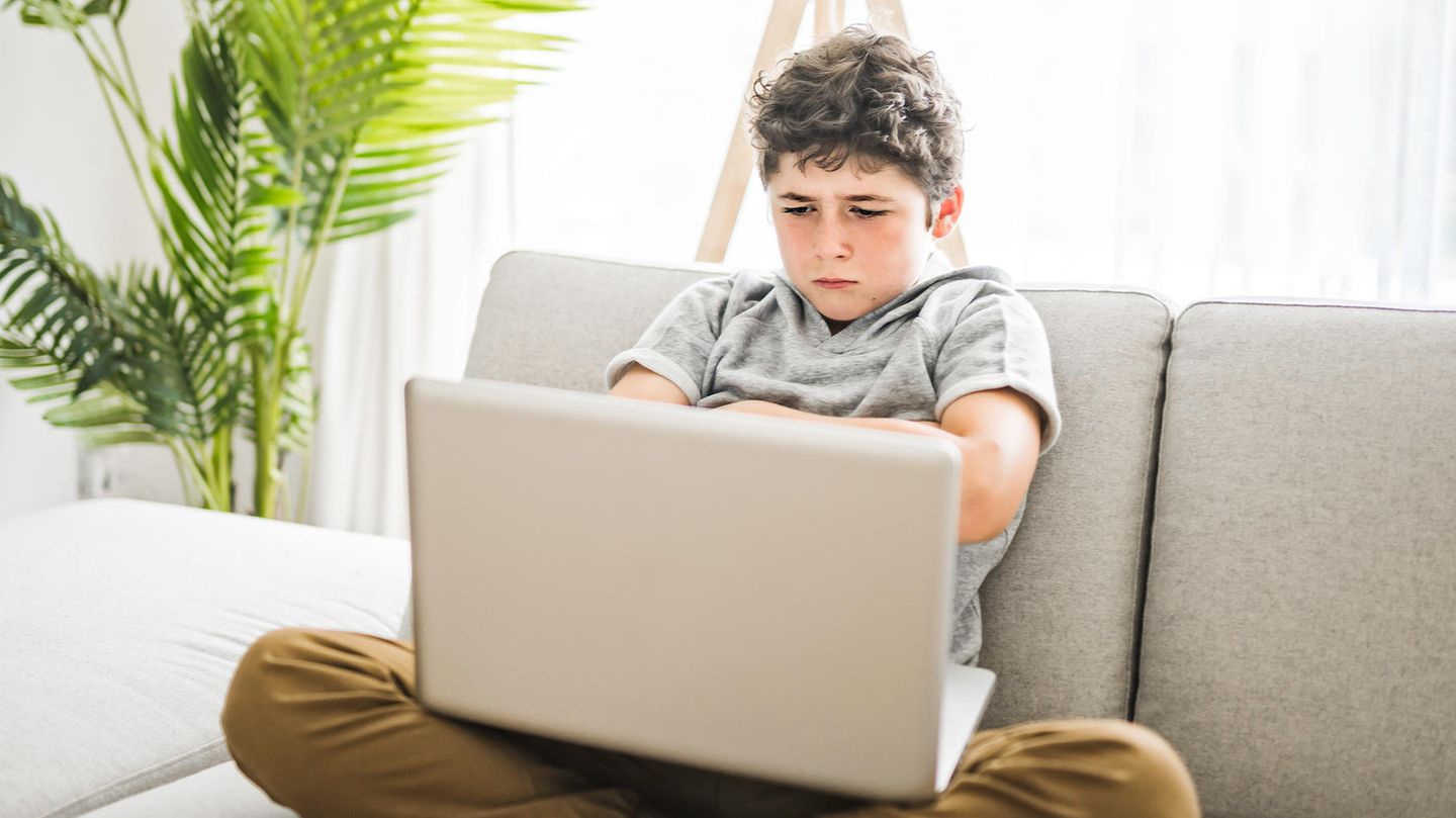 Junge sitzt enttäuscht am Laptop