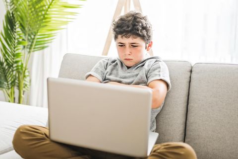Junge sitzt enttäuscht am Laptop