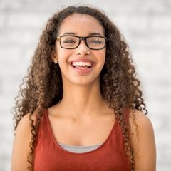 Eine junge Frau mit Brille, lachend