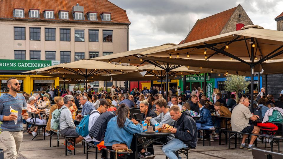 Menschen sitzen an Tischen auf einem Markt in Kopnehagen