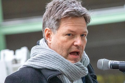 Robert Habeck trägt einen Mantel und einen Schal und spricht in ein Mikrofon