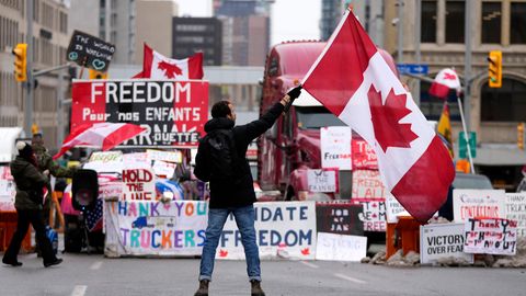 Demonstrant schwenkt Kanada Flagge vor einem parkenden Lkws in Ottawa.