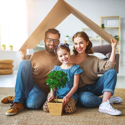Familie sitzt unter einem Pappdach in einer Wohnung