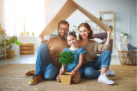 Familie sitzt unter einem Pappdach in einer Wohnung