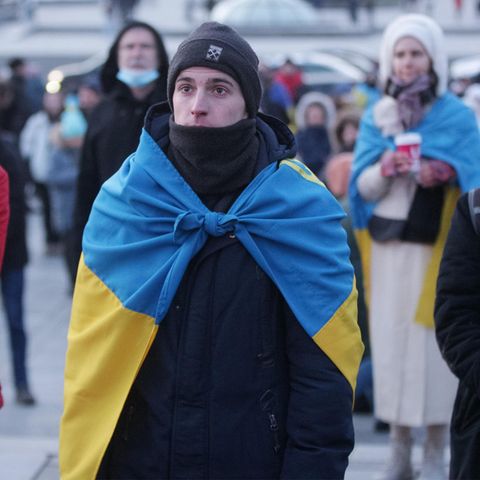 Junger Mann mit der ukrainischen Flagge um die Schultern in Kiew