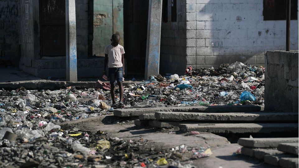 Mädchen aus Haiti steht vor den Trümmern eines Gebäudes