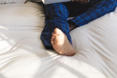 Matratzen im Check bei Stiftung Warentest: Mann sitzt auf einer Matratze und arbeitet am Laptop (Symbolbild)