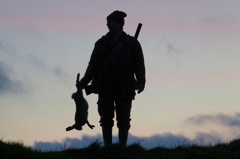 Mann mit erlegtem Hase im Gegenlicht