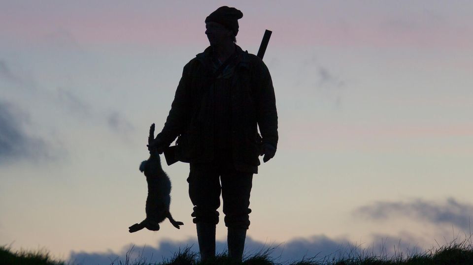 Mann mit erlegtem Hase im Gegenlicht