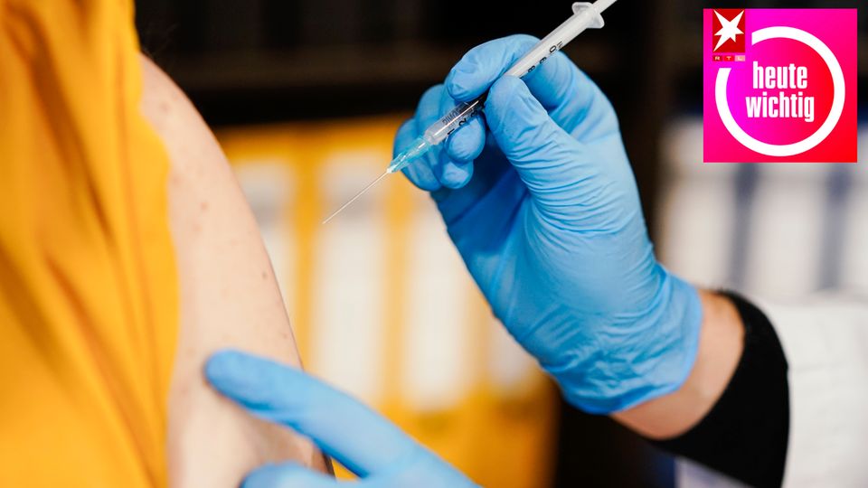 Hand mit blauem Handschuh setzt eine Impfung