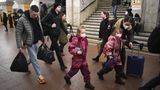 Ein Mann und eine Frau gehen mit Gepäck und zwei Mädchen in rosa gemusterten Schneeanzügen durch eine Metro-Station