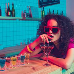 Klut-Drinks der 80er: Eine Frau liegt auf dem Tresen und trinkt einen Cocktail.