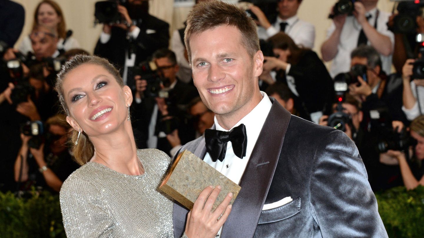 Tom Brady lacht mit seiner Frau Gisele Bündchen auf dem roten Teppich in die Kamera