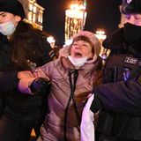 Eine Frau setzt ihren Protest gegen den Krieg auch noch fort, als zwei Polizisten sie abführen. 