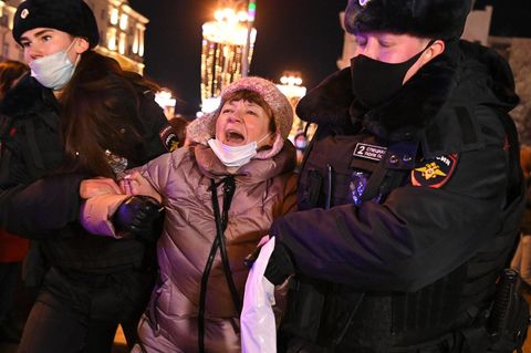 Eine Frau setzt ihren Protest gegen den Krieg auch noch fort, als zwei Polizisten sie abführen. 