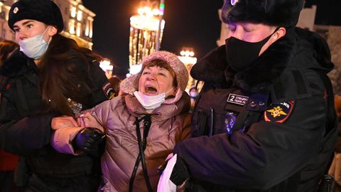Eine Frau setzt ihren Protest gegen den Krieg auch noch fort, als zwei Polizisten sie abführen. 